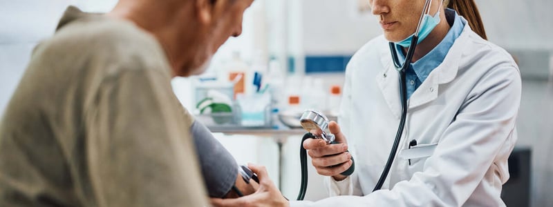 Junge Ärztin misst bei ihrem Patienten den Blutdruck.
