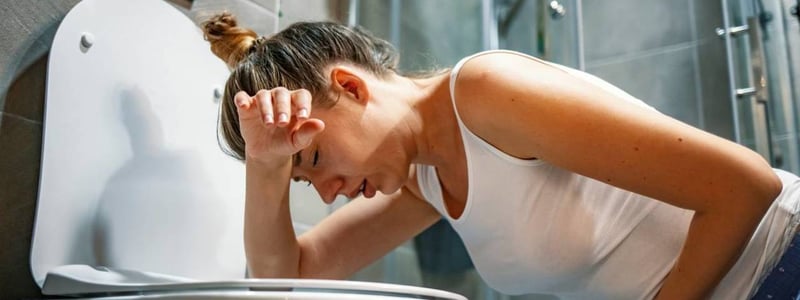 Frau erbricht sich auf der Toilette.
