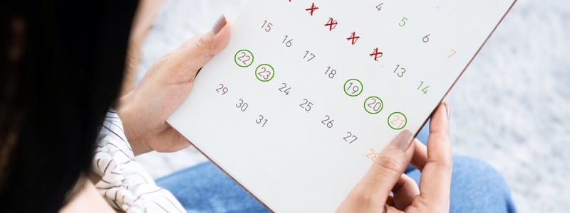 Frau betrachtet Zykluskalender in ihrer Hand.