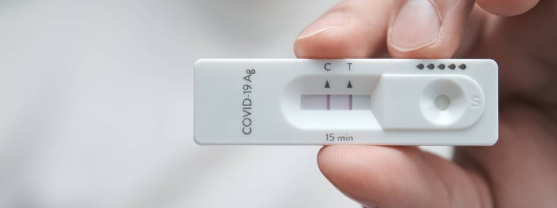 Auf dem Bild ist eine Hand zu sehen, die einen positiven Corona-Schnelltest hält.