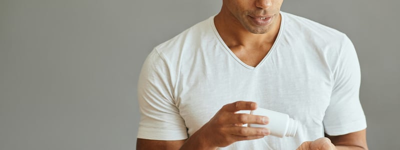 Ein junger mann mit Glatze schüttet sich Tabletten in die Hand.