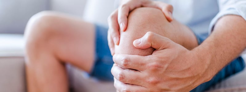 Ein Mann hält sich vor Schmerzen das Knie.