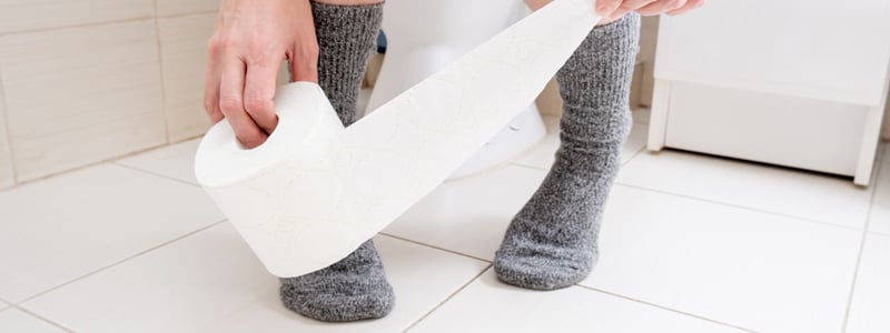 Hände greifen nach Toilettenpapier auf Toilette.