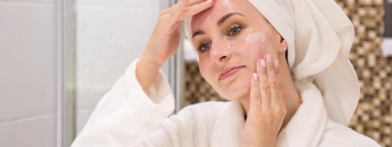 Frau im Badezimmer behandelt ihr Gesicht mit Gel.