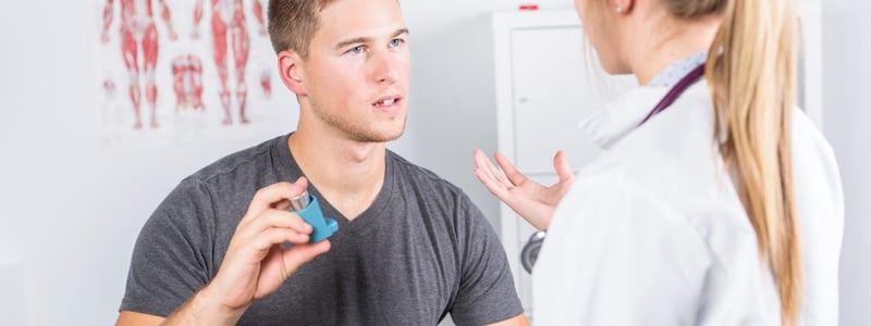 Ein Patient hält ein Asthmaspray in der Hand und redet mit einer Ärztin.