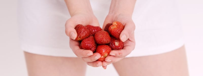 Frau hält Erdbeeren in der Hand.