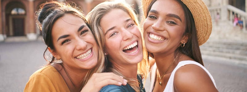 Drei Frauen lachen in die Kamera.