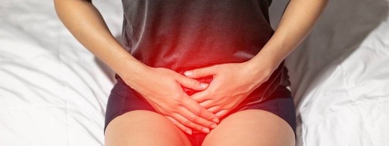 Blasenentzündung: Frau sitzt mit Schmerzen auf dem Bett