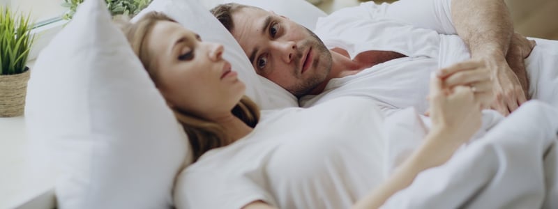 Ein Paar liegt im Bett und führt ein Gespräch.