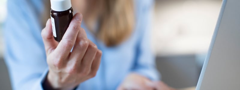 Frau sitzt am Laptop und bestellt Medikamente nach.