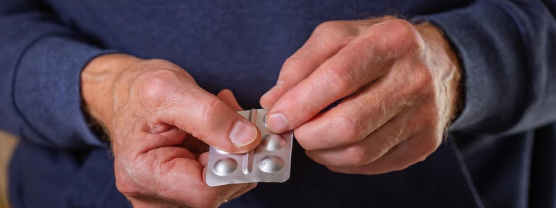 Die Hände eines älteren Mannes halten einen Tablettenblister.