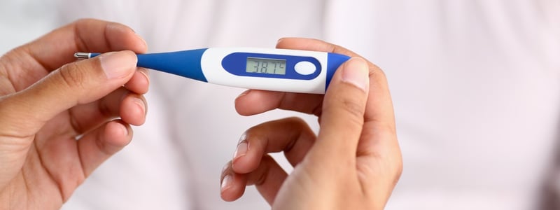 Ein Fieberthermometer zeigt 38,7 °C an.