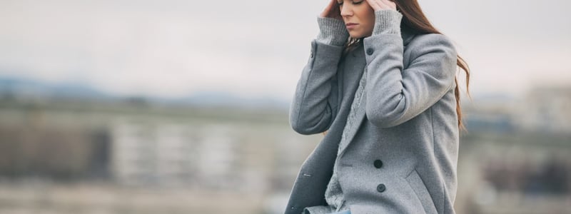 Junge Frau hat Kopfschmerzen durch Wetterumschwung.