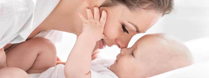 Junge Mutter kuschelt mit ihrem Baby.