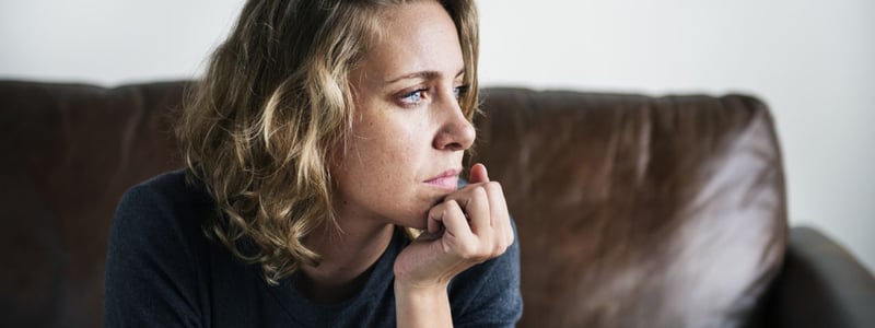 Frau mit innerer Unruhe nachdenklich auf Sofa.