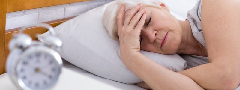 Frau liegt mit Migräne im Bett.