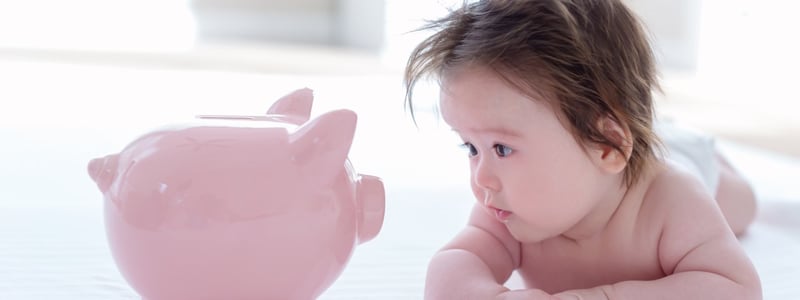 Es ist ein Baby mit einem Sparschwein zu sehen.